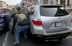 Tres agentes inmovilizan junto a su vehículo a un detenido en una calle de Boston.