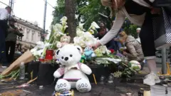 ljudi ostavljaju cveće, sveće i igračke ispred škole u kojoj su učenici ubijeni 