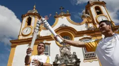 Atletas carregam a tocha olímpicaquina da loteriafrente a uma igreja no Brasilquina da loteria2016