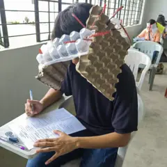 በእንኩላል መያዣ እቃ ፊቱን የሸፈነ ተማሪ