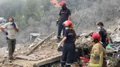 نحو 5 أفراد من الدفاع المدني اللبناني ورجل مدني يقفون فوق ركام مبنى متداعٍ جراء القصف الإسرائيلي