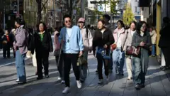 Turistas chineses caminham em uma rua do distrito comercial de Ginza, em Tóquio, no dia 22 de novembro de 2025