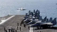 የአሜሪካ የጦር ጄቶች ከአውሮፕላን ጫኝ መርከብ ላይ ተነስተው ሲበሩ 