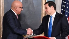 مارکو روبیو وزیر خارجه آمریکا با همتایش در حال دست دادن در حالیکه دو پوشه به دست دارند