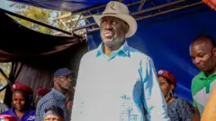 Raila Odinga standing wearing white wit hat