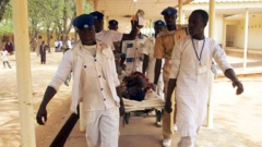 Awọn oṣiṣẹ eleto ilera to wọ aṣọ funfun n gbe alailera lọ sibi kan nile iwosan 