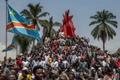 Des habitants grimpent sur un monument entouré de drapeaux congolais après un rassemblement organisé par des groupes de la société civile en soutien au mouvement M23 et contre le gouvernement central congolais à Bukavu le 22 février 2025.