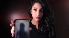 Monika Plaha cầm điện thoại cho thấy ảnh nude đã làm mờ