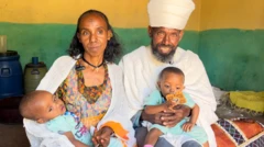 ሊቀ ትጉሃን ኣማረ ሃይሉን ወ/ሮ ካሕሱ ዕቡይ ምስ ማናቱ ደቆም ሓቚፎም ይርኣዩ። ልብሰ ክህነት ዝለበሱ ኣቦይ ቀሺ መስቀል ሒዞም ኣለዉ፡ ሓቚፎማ ዘለዉ ህጻን ጓሎም ነታ መስቀል ክትሕዛ እናፈተነት ትርአ።