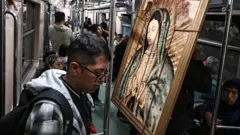 Un hombre viaja en el Metro de Ciudad de México y frente a él un cuadro de la Virgen de Guadalupe.