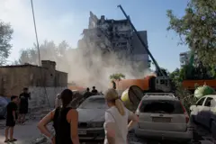 Kiev'de Rusya'nın saldırıları sonucu yıkılmış bir bina önünde durmuş insanlar