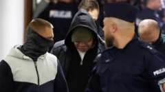 Група чоловіків, які частково приховують свої обличчя, йде коридором офіційної будівлі 