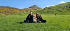 O casal está sentado na grama com a cachorra Gaia