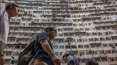 香港街頭，行人背後是密密麻麻的住宅樓