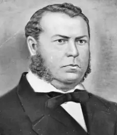 Retrato de Conceição; ele está de terno e gravata e demonstra olhar sério