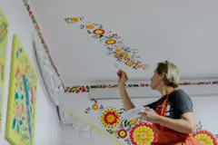 Una mujer hace dibujos en la pared del centro infantil Uniendo Corazones.