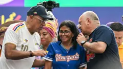Jorge Rodríguez conversa com Diosdado Cabello, com Delcy Rodríguez entre eles. Nenhum deles está vestido de vermelho