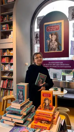 Катерина Штанко у книгарні, перед нею розкладені наклади двох її книг: "Вершники дощу" та "Дракони, вперед"