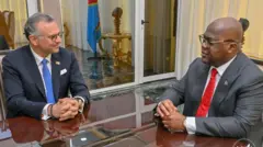 Massad Boulos, umujyanama mukuru wa Perezida w'Amerika Donald Trump kuri Afurika, i Kinshasa, muri RDC, mu kiganiro na Perezida Félix Tshisekedi. Bombi bicaye ku ntebe, bambaye kositimu, ibiganza biri ku meza. Ibendera rya RDC riraboneka kuri iyi foto yo ku wa kane, ku itariki ya 3 Mata (4) mu mwaka wa 2025. 