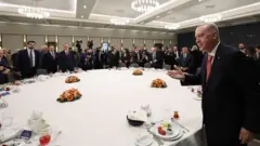 Cumhurbaşkanı Erdoğan yuvarlak bir masada çevredekileri selamlıyor