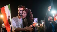 İran hükümeti yanlısı bir gösteride sloganlar atanlar arasında genç bir İranlı çift birbirine sarılıyor.