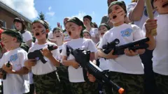 Crianças gritam enquanto seguram espingardas de brinquedo, durante o jogo militar-patriótico 'Zarnitsa' no jardim da infância em Stavropol, no dia 5 de junho de 2015
