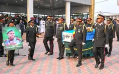 Abasirikare baherekeje isanduku y'abapfiye iriho indabo n'ibendera ry'igihugu n'undi uri imbere afite ifoto nini iriho Jenerali Peter Cirimwami mu muhango wo kumusezeraho