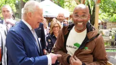 King Charles laughing as he greets peope in New York. Pictured with a happy man who looks at the camera with big smile. 