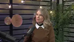 Rita Lobo usa um suéter marrom. Ela está sentada em um estúdio, falando ao microfone.