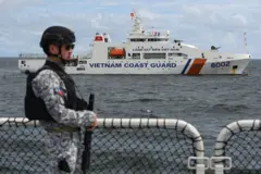 A member of the Philippine Coast Guard personnel stands guard aboard the Gabriela Silang ship as a Vietnamese Coast Guard ship sails past during a joint maritime exercise off Bataan in the disputed South China Sea on August 9, 2024. 
