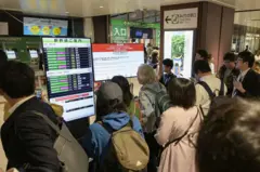 Passageiros observam telas anunciando suspensão de serviço de trens na estação de Sendai, no norte do Japão, nesta segunda-feira (20/04)