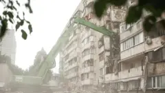 Екскаватор ДСНС працює на місці зруйнованого внаслідок російської атаки житлового будинку в Києві. 7 липня 2026 року.