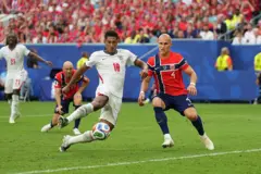 O meio-campista da Inglaterra Jude Bellingham marca um gol enquanto o defensor da Noruega Leo Østigård tenta a defesa, durante a partida das quartas de final da Copa do Mundo, em 11 de julho de 2026.