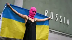 Участница Pussy Riot держит украинский флаг перед павильоном России 