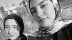 Baş örtülü iki genç kız yan yana kameraya bakıyor