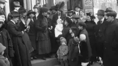 Uma pequena multidão se reúne em torno de Margaret Sanger e sua irmã, Ethel Byrne, no tribunal