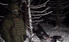 військовий стоїть біля дрону у зимовому лісі