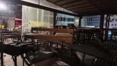 El interior oscuro de un bar muestra mesas y asientos tirados.