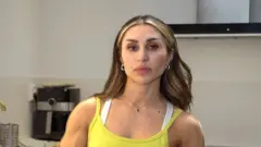 Roya Karimi looks at the camera wearing a yellow tank top