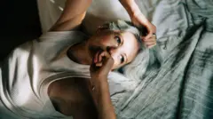 Mulher deitada na cama, acordada