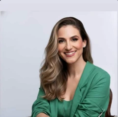 Foto de estúdio da psicóloga Maísa Brum, que usa uma blusa e um blazer verdes