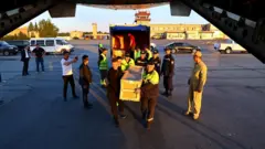 Тегишли ташкилотлар ходимлари жасадлар ортилган қутиларни самолётга юкламоқда.
