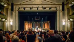 Foto tirada da plateia mostra o palco