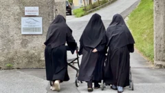 As três freiras se afastam de costas para a câmera