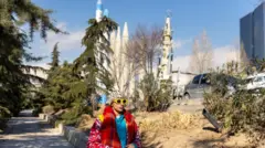 طهران، إيران – 16 يناير/كانون الثاني 2026: تمرّ امرأة بجانب صواريخ معروضة في معرض دائم للأسلحة في طهران. 