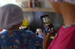 Uma mãe filmando uma criança cozinhando