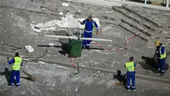дворники убирают улицу в румынском Галате, где дрон врезался в многоэтажку