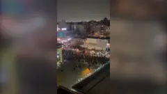 夜の都市の大通りを大勢が行進している