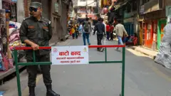 काठमाण्डू महानगर प्रहरीका एक कर्मचारी 'बाटो बन्द' लेखिएको बोर्डसँगै