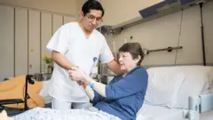 Foto de um enfermeiro cuidando de uma senhora em uma cama.